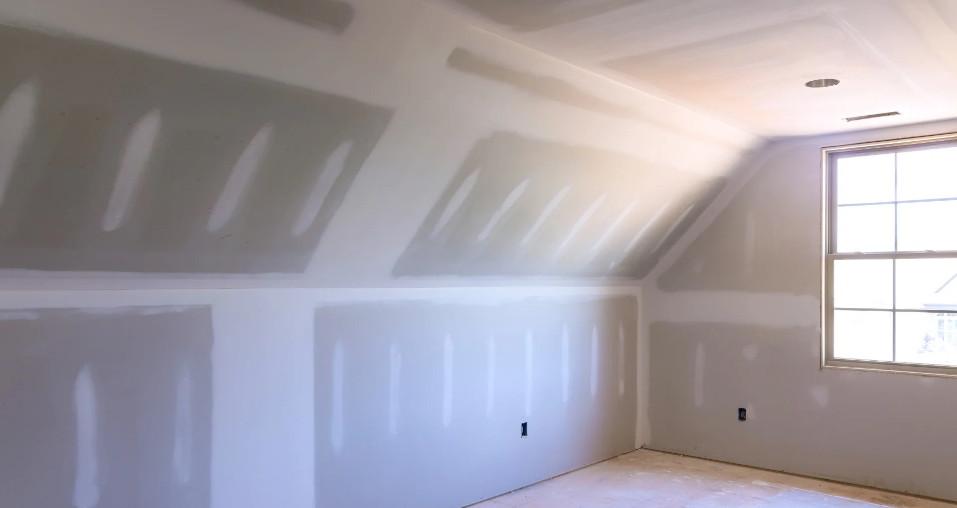 Frisch eingerichteter Raum mit Trockenbauwänden, durch den natürliches Licht durch das Fenster strömt